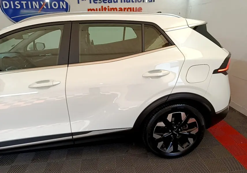 Profil droit du Kia Sportage blanc 2022 hybride rechargeable, avec jantes noires et feux arrière LED distinctifs.