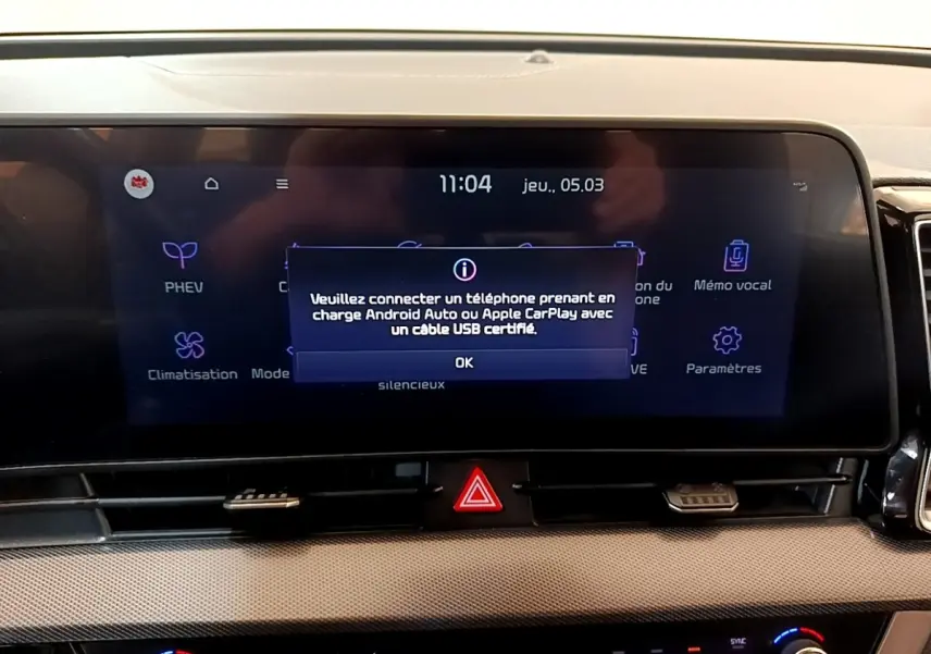 Gros plan sur l'écran tactile central du tableau de bord du Kia Sportage blanc, affichant un message de connexion USB.