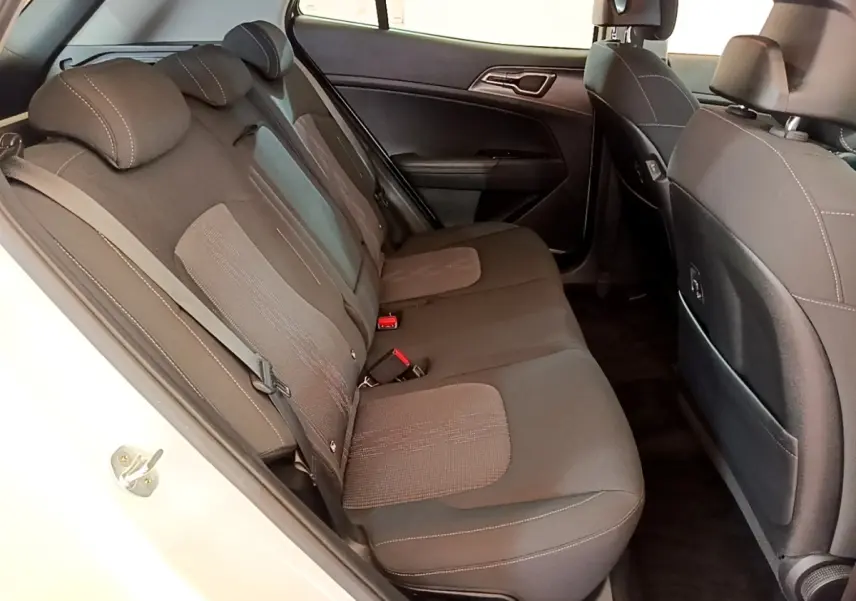 Vue intérieure côté gauche des sièges arrière en tissu gris du KIA Sportage blanc 2022, avec ceintures et appuie-têtes visibles.