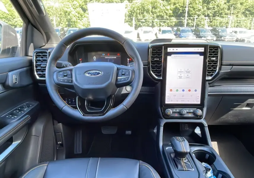Vue intérieure avant du Ford Ranger 2026, tableau de bord noir avec écran tactile vertical et volant cuir multifonctions.
