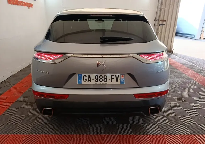 Vue arrière d’un DS7 Crossback E-TENSE gris foncé avec feux arrière LED allumés et double sortie d’échappement carrée.