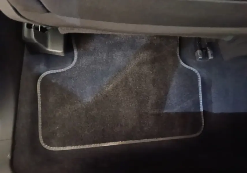 Vue rapprochée du tapis de sol noir côté passager arrière du DS7 Crossback E-TENSE 225 BUSINESS gris foncé.