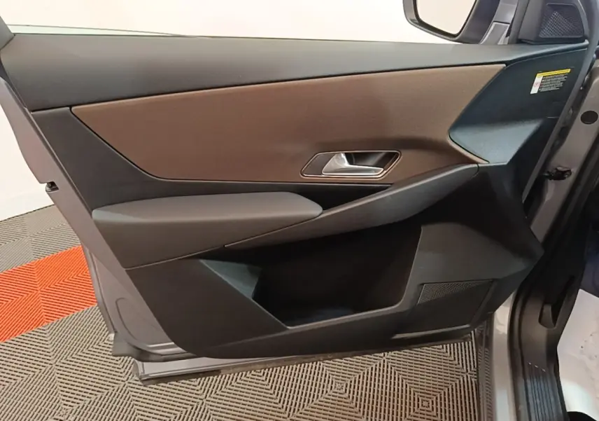 Vue rapprochée de la porte avant droite du DS7 Crossback gris foncé, avec garniture marron et poignée argentée.