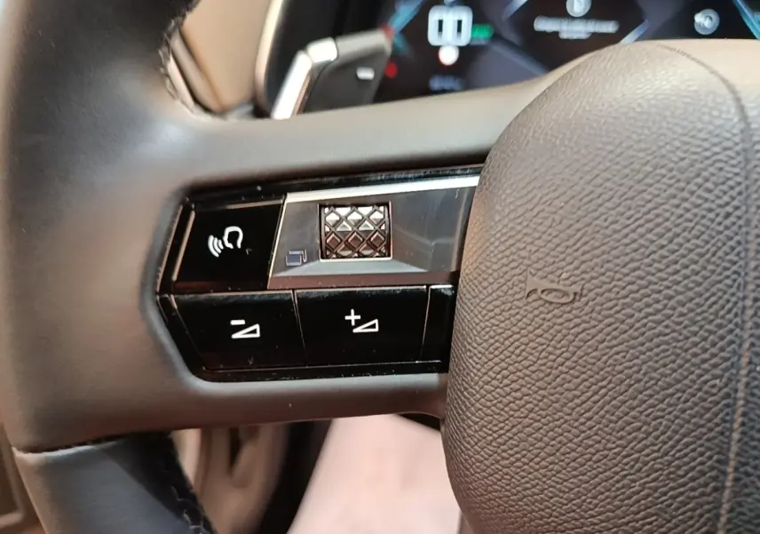 Gros plan sur le volant cuir multifonctions du DS7 Crossback E-TENSE 225 Business, avec commandes de volume et reconnaissance vocale.