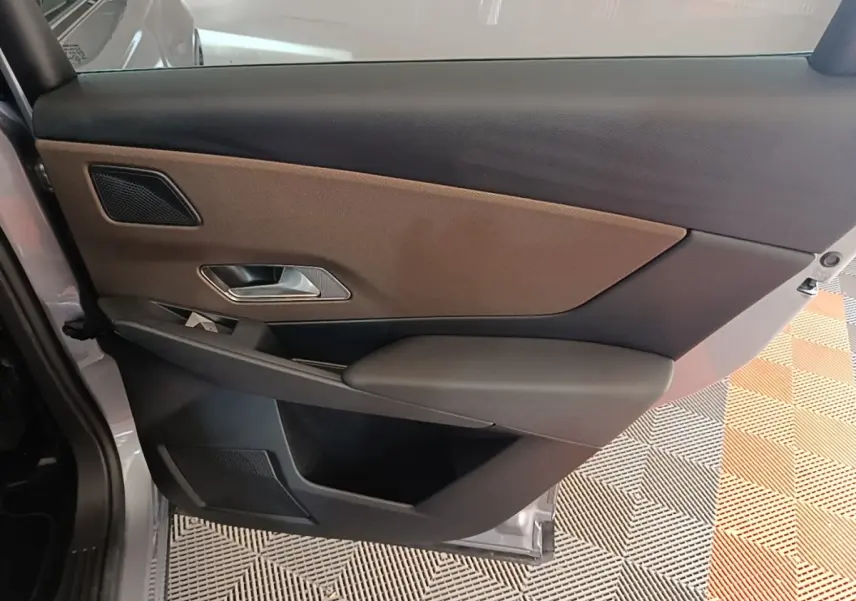 Vue intérieure de la porte arrière gauche du DS7 Crossback gris foncé, avec habillage bicolore marron et noir.