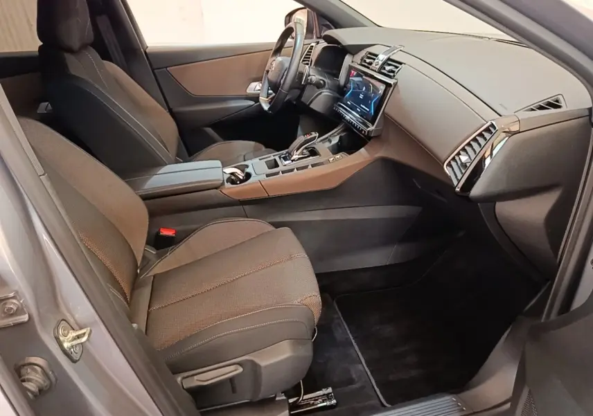Vue intérieure côté passager avant du DS7 Crossback E-TENSE 225 Business avec sièges tissu gris et tableau de bord moderne.