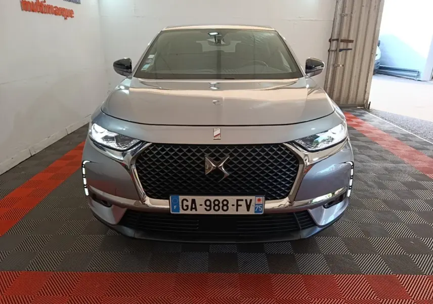 Vue avant d'un DS7 Crossback gris foncé avec calandre distinctive et feux LED allumés en intérieur.