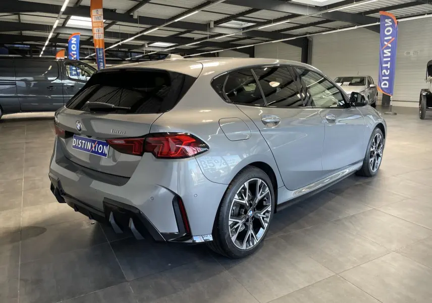 BMW Série 1 120d M Sport gris vue 3/4 arrière droit, jantes 18 pouces bicolores et diffuseur noir M Sport.