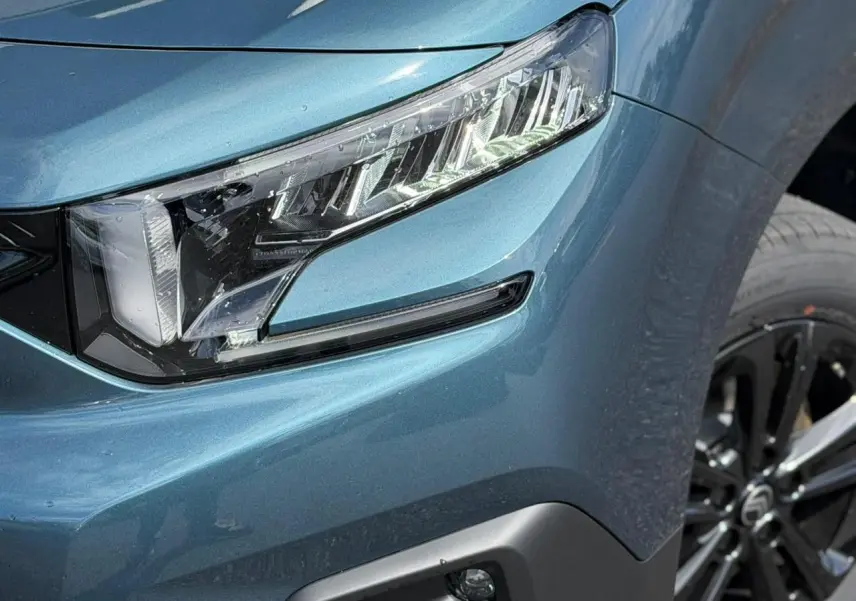 Gros plan sur le phare avant droit et la jante alliage noire du Citroën Berlingo Multispace Bleu Kiama métallisé.