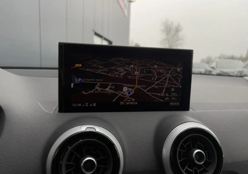 Vue intérieure du tableau de bord de l'Audi Q2 30 TFSI S-Line 2024, écran de navigation et aérateurs ronds noirs.