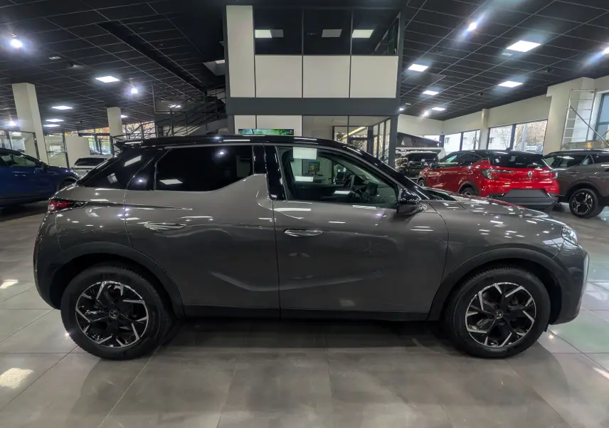 Vue latérale droite d'un DS3 Crossback 2022 gris Platinium avec toit noir et jantes noires en concession.