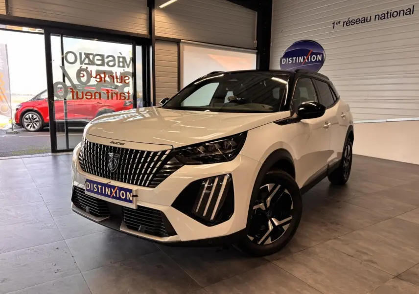 Peugeot 2008 blanc vue 3/4 avant droit en intérieur, avec calandre verticale et jantes noires distinctives.