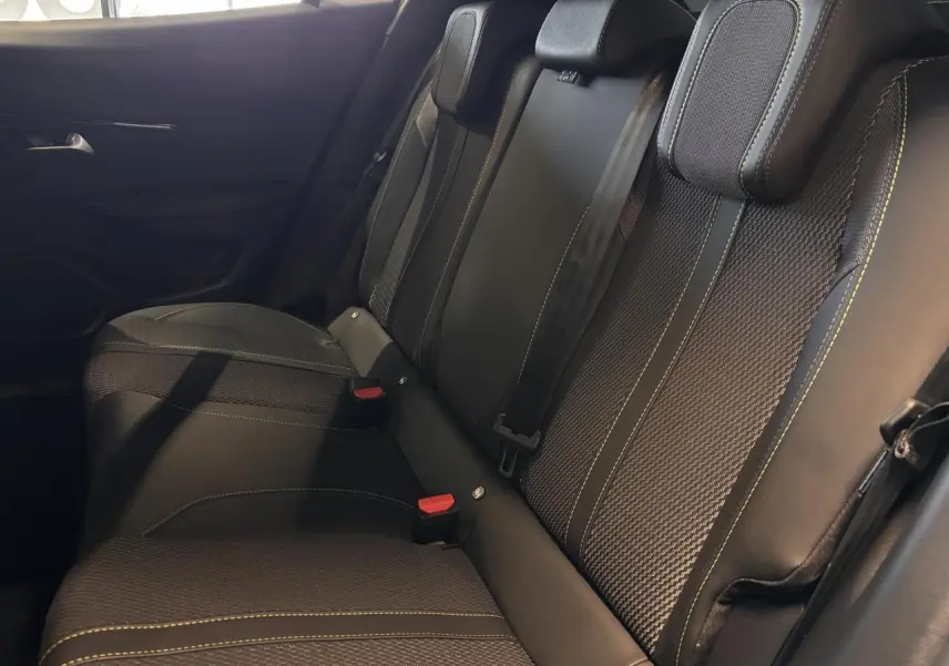 Vue latérale intérieure des sièges arrière noirs avec surpiqûres jaunes du Peugeot 2008 hybride blanc 2025.