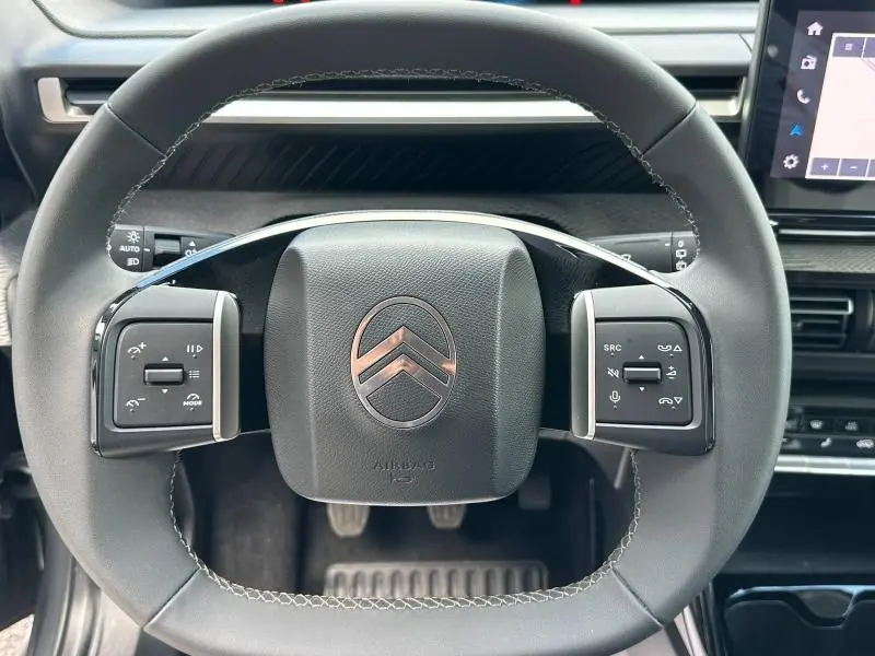 Vue rapprochée du volant noir de la Citroën C3 1.2 Turbo 100ch MAX 2025 avec commandes intégrées et logo chromé central.