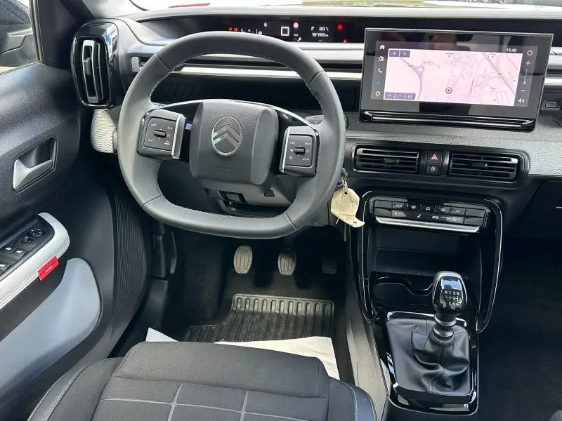 Vue intérieure frontale du poste de conduite gris d'une Citroën C3 1.2 Turbo 2025 avec écran tactile GPS et boîte manuelle.