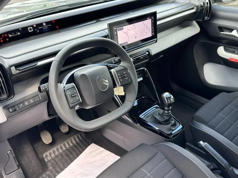 Vue intérieure côté conducteur de la Citroën C3 1.2 Turbo 100ch MAX avec volant multifonctions et écran tactile GPS.