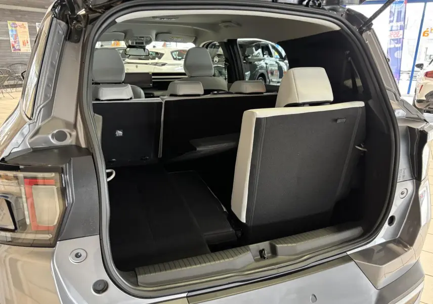 Coffre ouvert vue arrière d’un Citroën C3 Aircross gris avec banquette arrière rabattue et sièges blancs visibles.