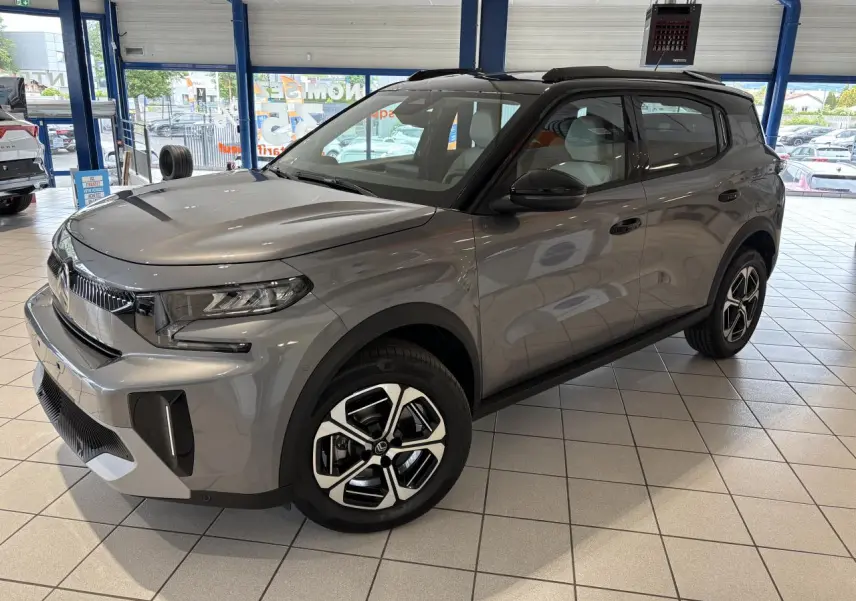 Citroën C3 Aircross 2026 gris métallisé avec toit noir, vue 3/4 avant droit en showroom intérieur.