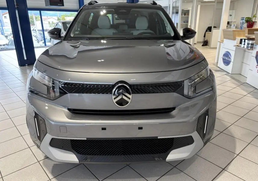 Vue avant d’un Citroën C3 Aircross 2026 gris métallisé avec toit noir, en showroom lumineux.