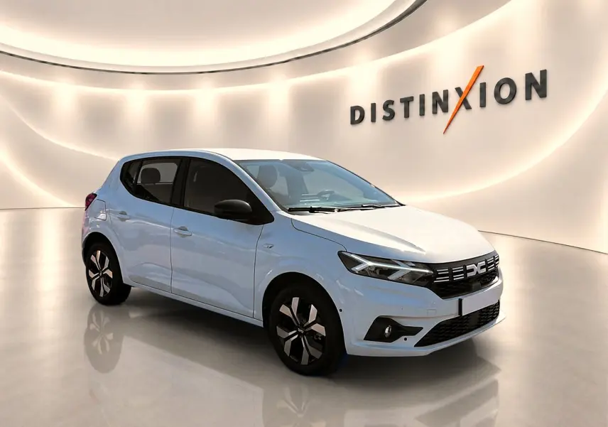 Dacia Sandero blanc vue 3/4 avant droit en intérieur avec jantes alu et calandre noire distinctive.