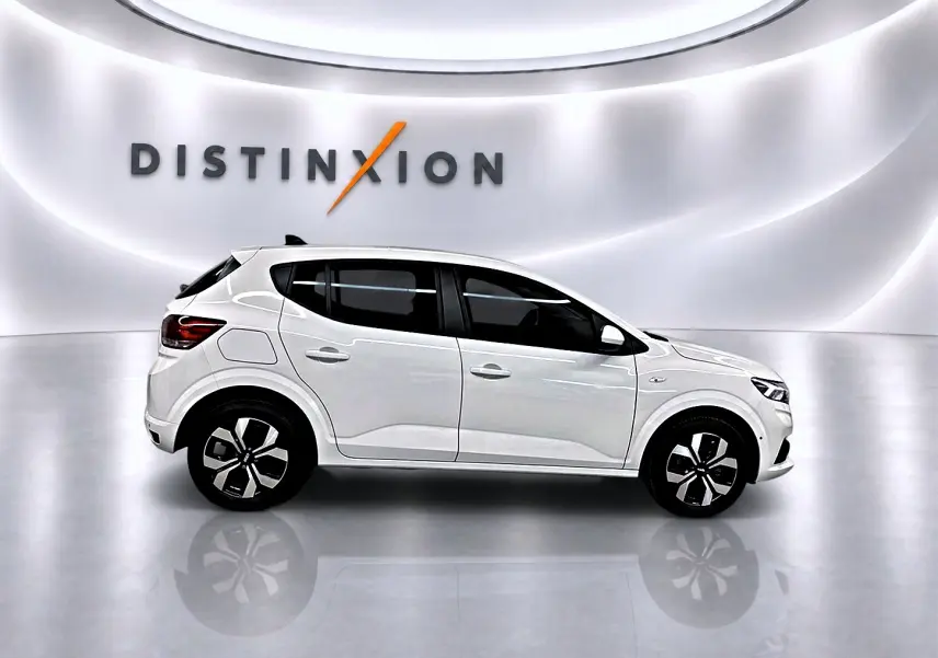 Profil droit d'une Dacia Sandero blanche 2025 dans un studio lumineux avec jantes alliage et vitres teintées.