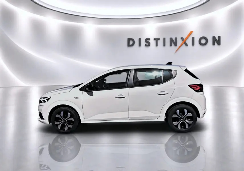 Profil droit d'une Dacia Sandero blanche 2025 dans un studio lumineux avec jantes alliage noires et logo Distinxion en arrière-plan.