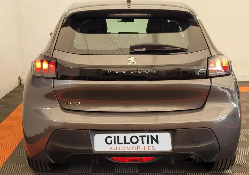 Vue arrière d'une Peugeot 208 gris foncé 2023 avec feux arrière allumés et logo Peugeot visible.