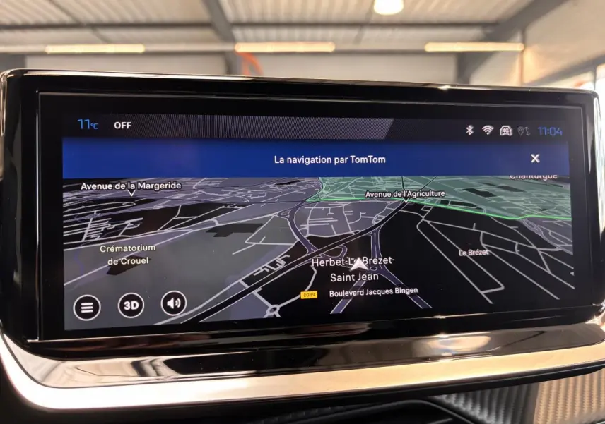 Écran tactile du système de navigation TomTom dans un Peugeot 2008 gris, affichant une carte en mode 3D.