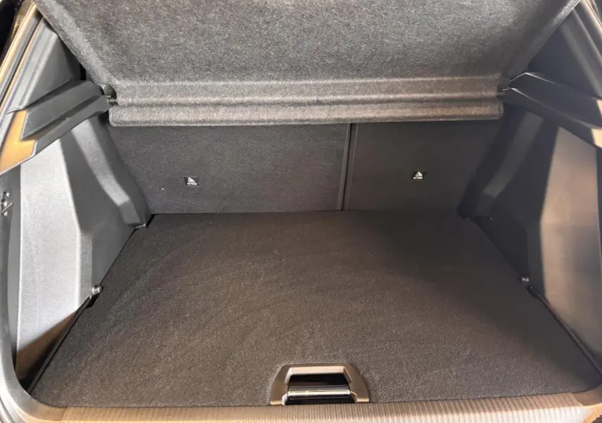 Coffre ouvert du Peugeot 2008 gris 2025, montrant l'espace de rangement et la couverture de coffre relevée.