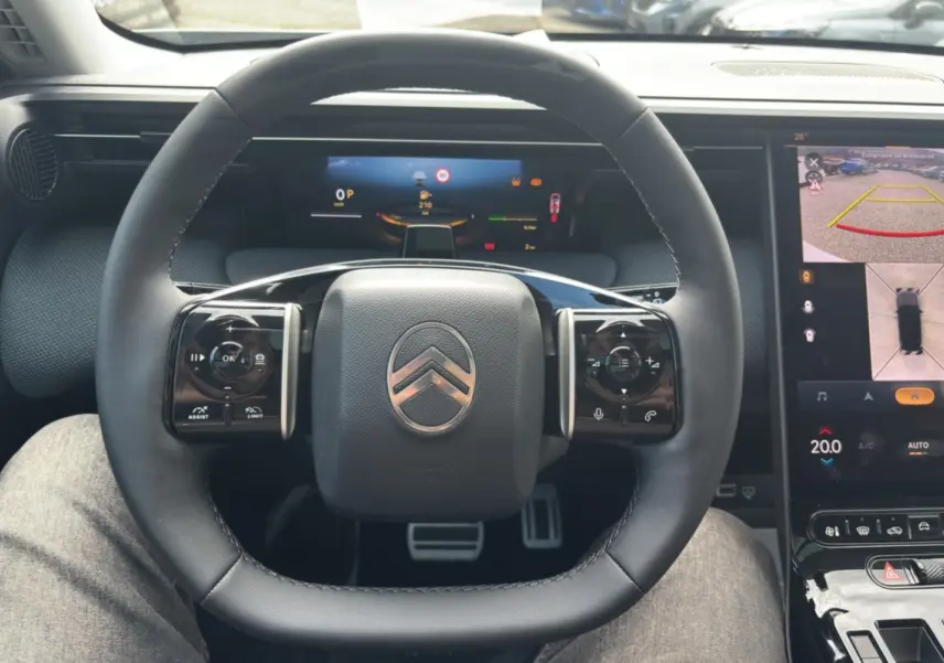 Vue intérieure centrée sur le volant cuir multifonctions d'une Citroën C5 Aircross 2026 avec écran numérique et caméra 360° affichée.