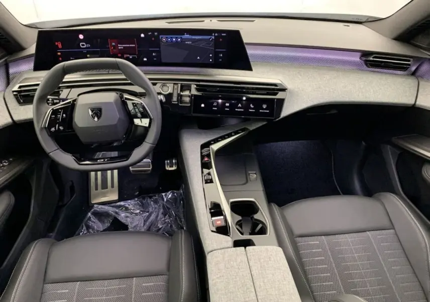 Vue intérieure avant du Peugeot 3008 Hybrid 2026, tableau de bord numérique large et sellerie cuir noire avec console centrale grise.