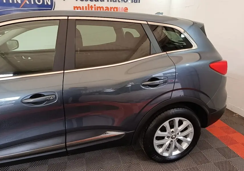 Vue latérale droite du Renault Kadjar Business gris foncé, mettant en valeur la porte arrière et la roue arrière.