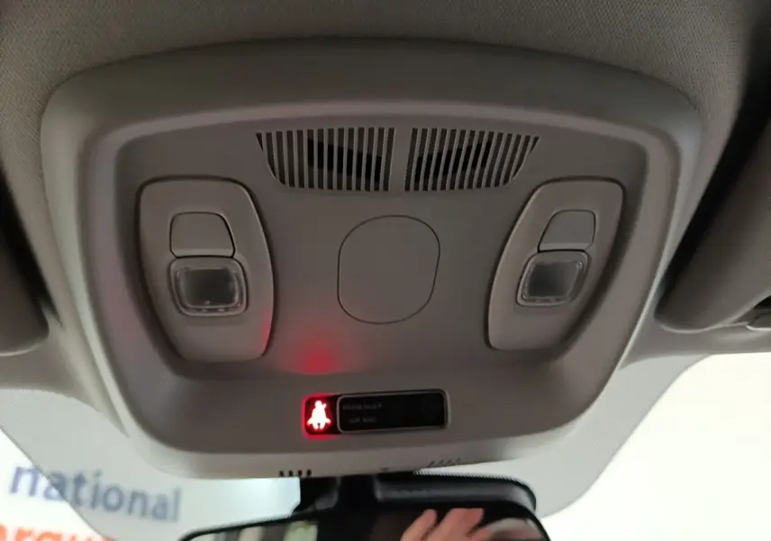 Plafonnier intérieur avec éclairage et témoin de ceinture allumé dans un Renault Kadjar gris foncé, vue vers l'avant.