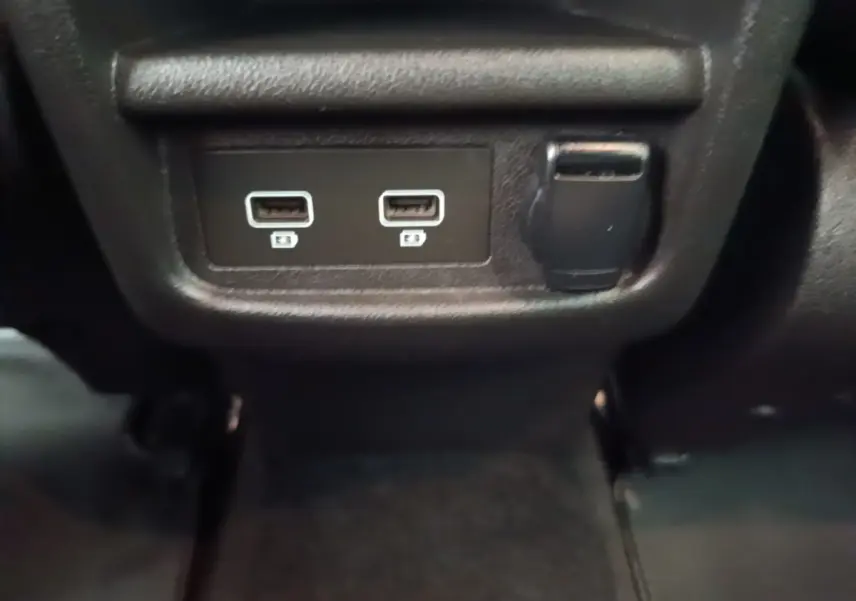 Prise USB double et prise 12V noire en gros plan à l'arrière du Renault Kadjar Business Blue dCi 115 EDC 2021 gris foncé.