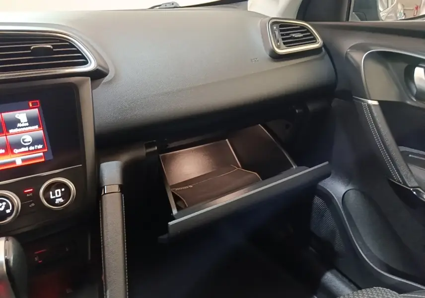 Intérieur du Renault Kadjar Business 2021, vue côté passager sur boîte à gants ouverte et tableau de bord noir.
