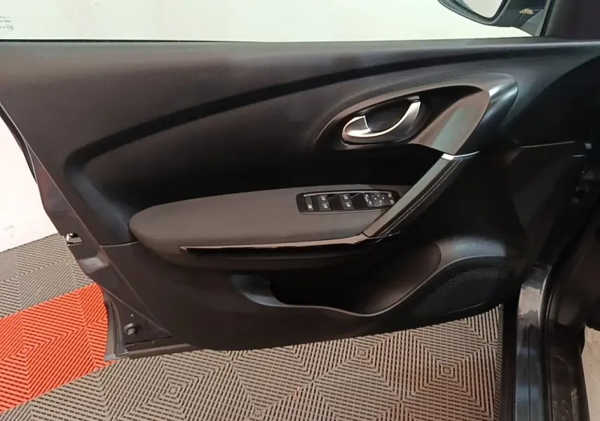 Vue intérieure de la porte avant gauche du Renault Kadjar gris foncé, avec commandes des vitres et poignée argentée.