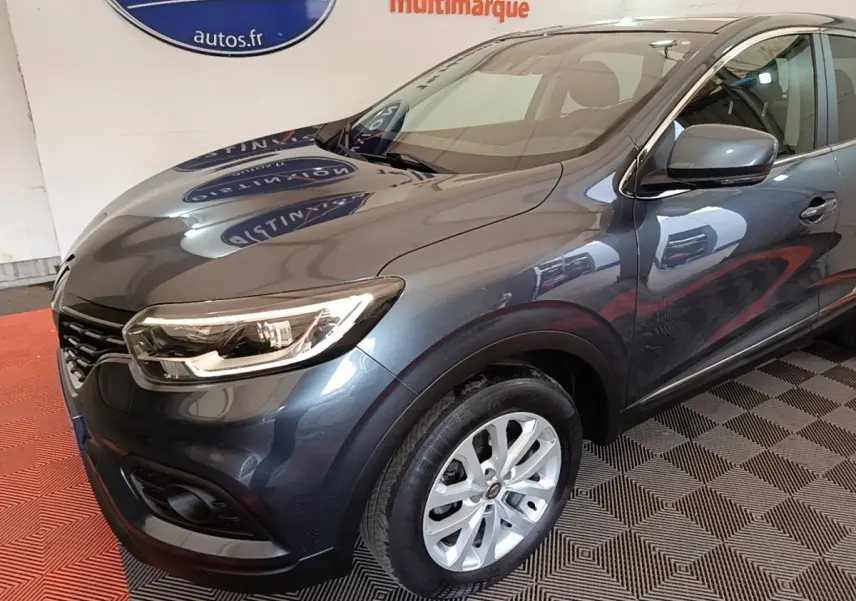 Vue 3/4 avant droit d’un Renault Kadjar Business gris foncé avec phares allumés et jantes argentées.