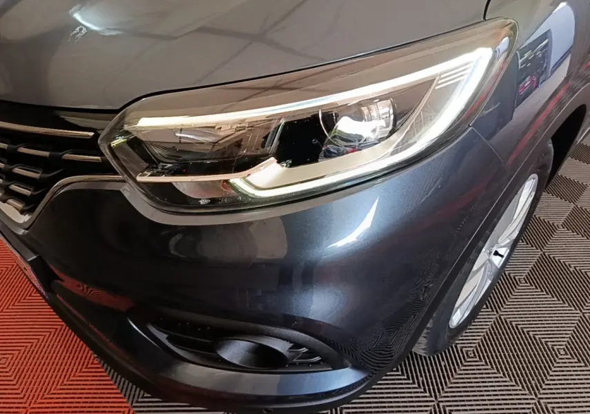 Gros plan sur l'avant droit du Renault Kadjar gris foncé, mettant en valeur le phare LED et la calandre.