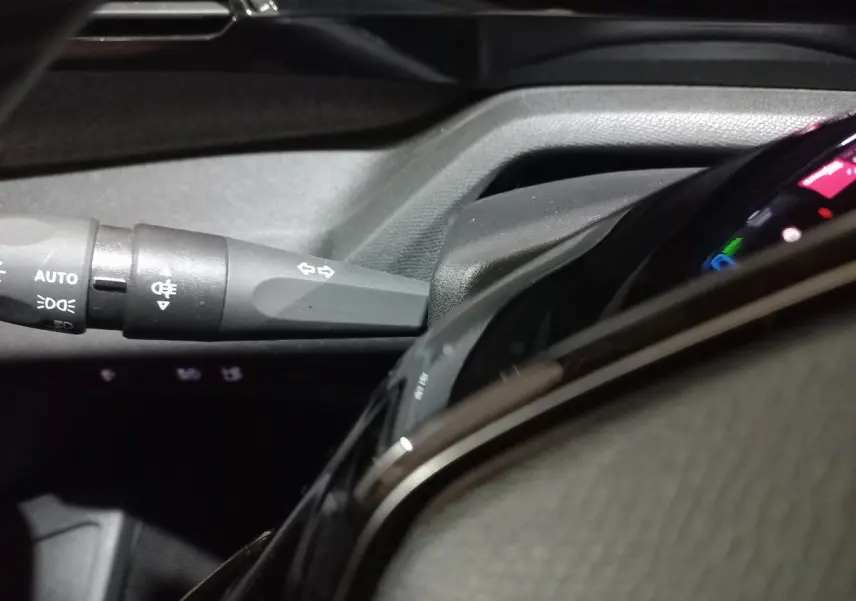 Gros plan sur la commande des clignotants et partie du combiné d'instruments numérique du Peugeot 308 PHEV 180 E-EAT8 Allure.