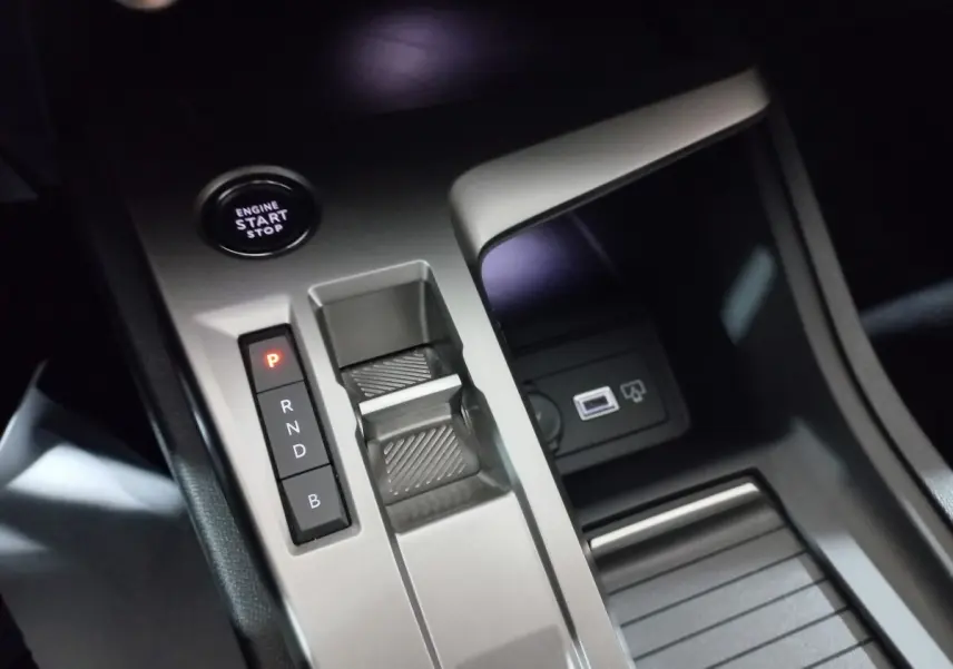 Gros plan sur la console centrale grise de la Peugeot 308 PHEV 180 E-EAT8 Allure avec bouton start et sélecteur de boîte auto.