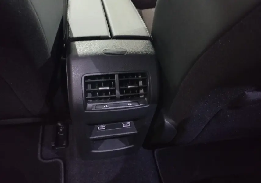 Vue rapprochée de la console centrale arrière noire avec bouches d’aération et ports USB de la Peugeot 308 PHEV 2025.