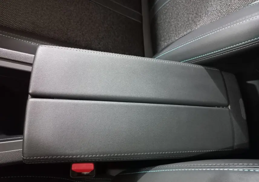 Accoudoir central en cuir noir avec surpiqûres bleues dans l’habitacle d’une Peugeot 308 PHEV 180 E-EAT8 Allure 2025.