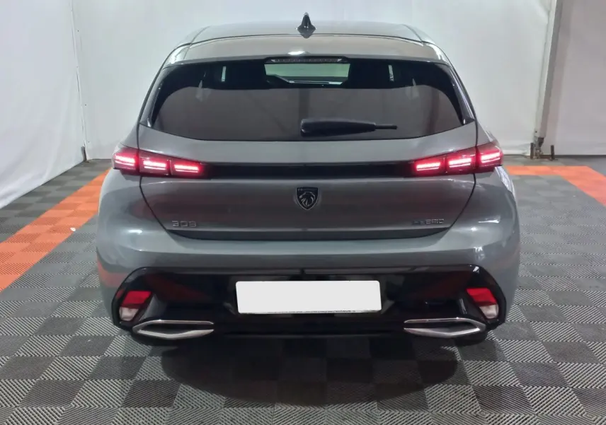 Vue arrière d’une Peugeot 308 PHEV 180 E-EAT8 Allure gris foncé avec feux LED allumés et double sortie d’échappement.