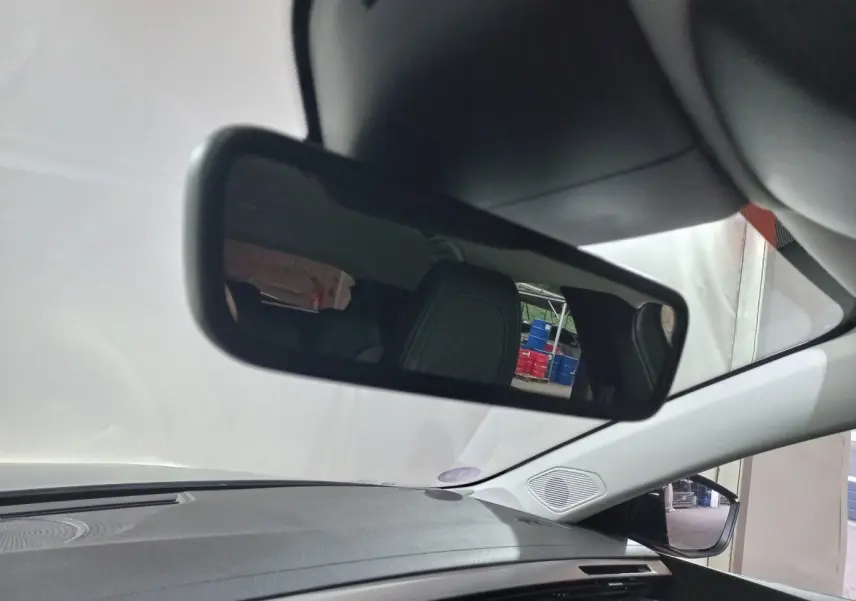 Vue intérieure du rétroviseur central d'une Peugeot 308 PHEV 180 E-EAT8 Allure 2025, avec tableau de bord gris et siège arrière visible.