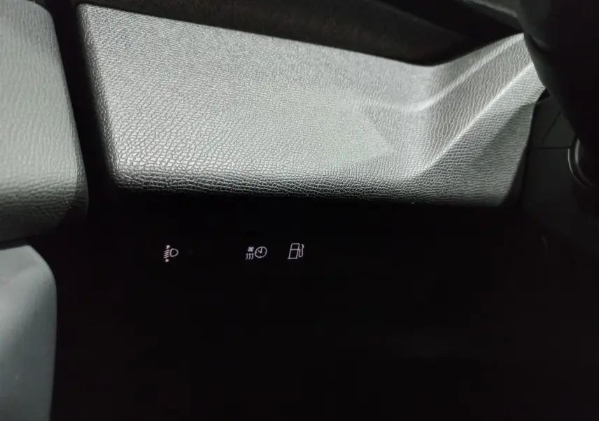 Gros plan sur la partie inférieure du tableau de bord gris texturé avec voyants lumineux blancs dans l'habitacle Peugeot 308 PHEV.