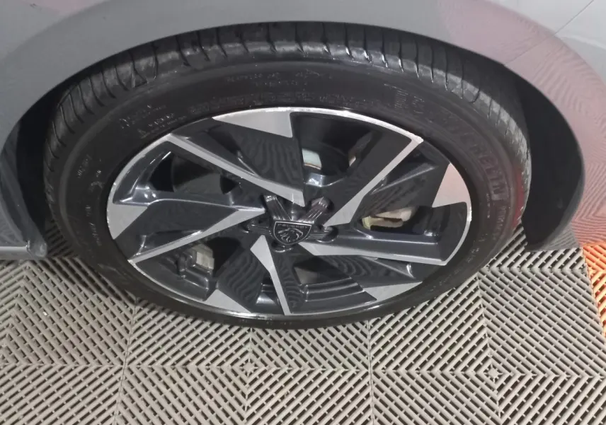 Gros plan sur la roue avant droite de la Peugeot 308 PHEV 180 E-EAT8 Allure gris foncé avec jante alliage noire et argent.