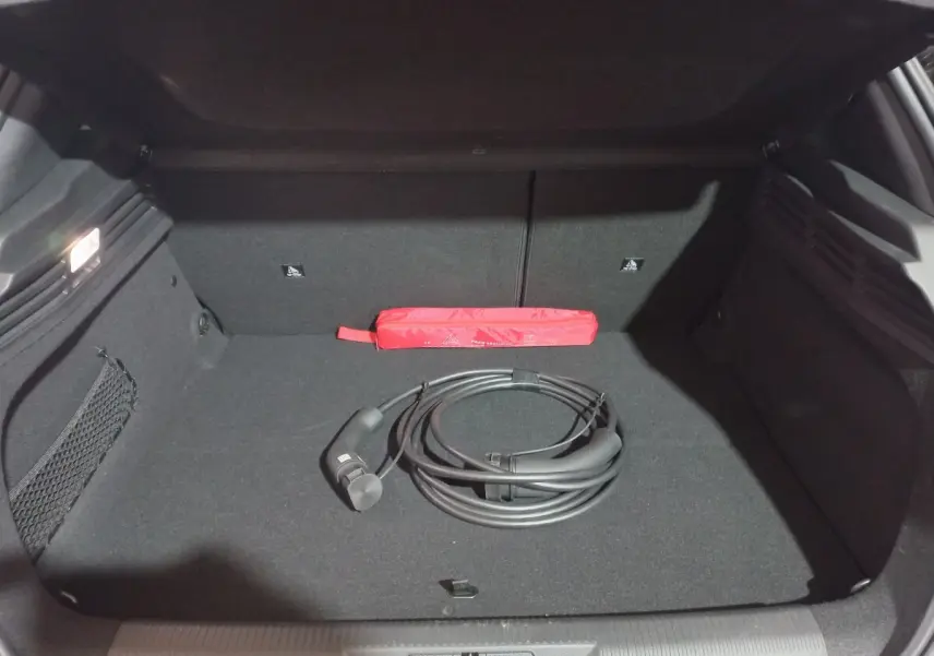 Coffre ouvert d’une Peugeot 308 PHEV gris foncé, montrant un câble de recharge noir et une trousse de secours rouge.