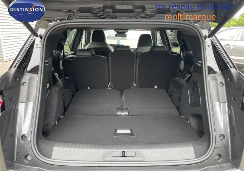 Coffre ouvert en vue arrière d'un Peugeot 5008 gris titane métal avec sièges arrière rabattus et toit noir visible.