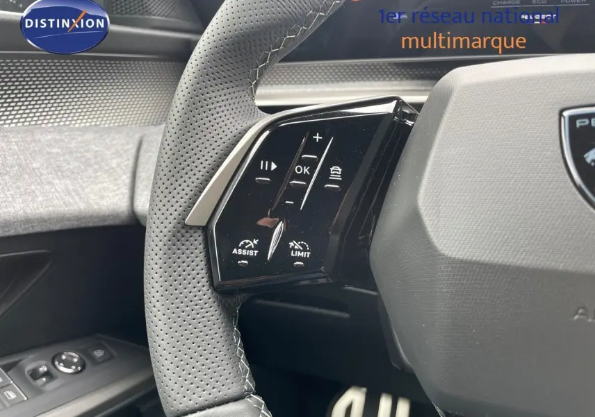 Gros plan sur le côté gauche du volant perforé du Peugeot 5008 Hybrid gris titane, avec commandes intégrées.