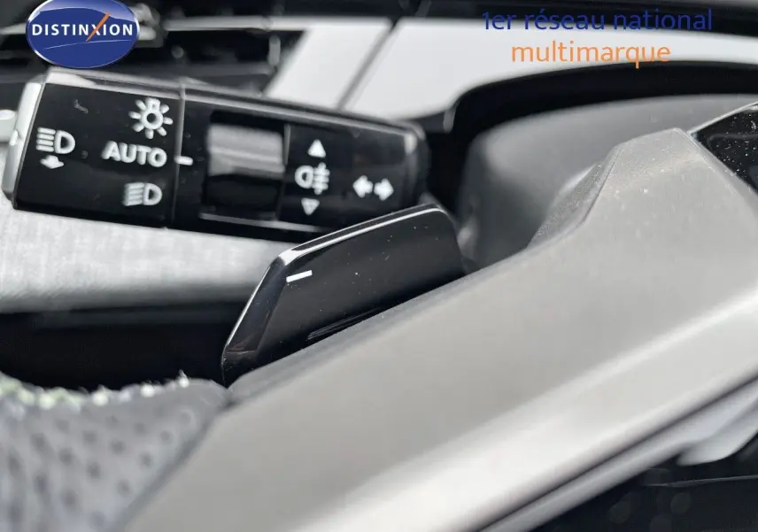 Gros plan sur la commande des feux et le volant gris clair du Peugeot 5008 Hybrid 2025, finition GT.